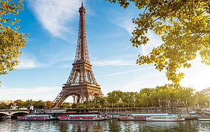 Eiffel Tower Rising Over the Seine River in Paris with Tour Boats and Lush Green Foliage HD wallpaper