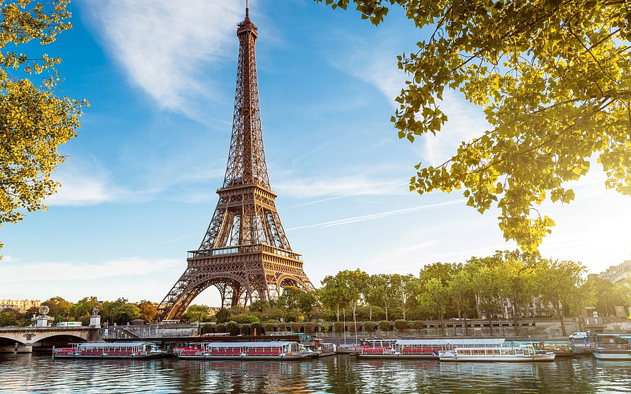 Eiffel Tower Rising Over the Seine River in Paris with Tour Boats and Lush Green Foliage HD wallpaper