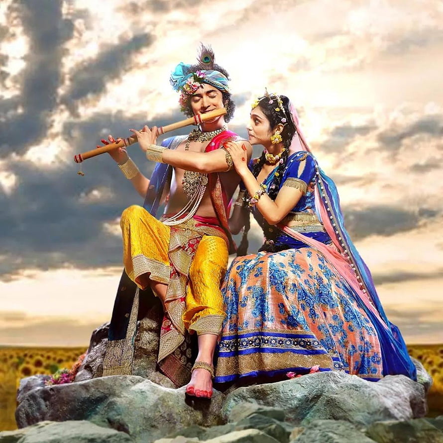 Radha Krishna Playing Flute in Traditional Indian Attire on a Rocky Outcrop HD phone wallpaper