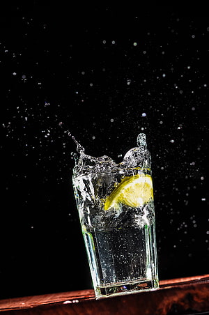 Refreshing Lemon Water Splash in Glass with Ice Cubes on Dark Background HD phone wallpaper