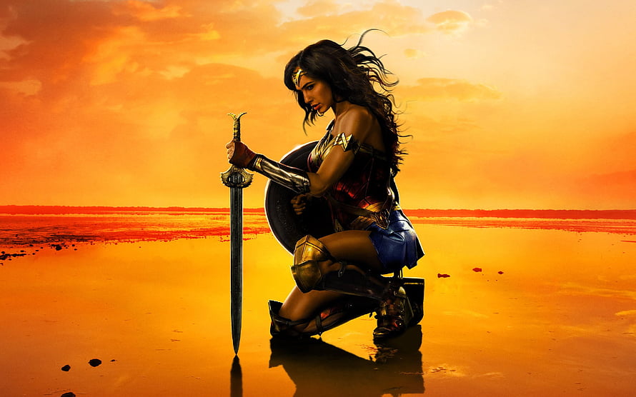 Wonder Woman kneeling with sword and shield against a fiery orange sunset HD wallpaper