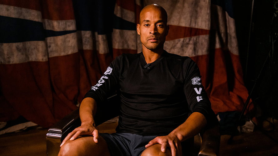David Goggins seated portrait in black athletic shirt against distressed American flag backdrop HD wallpaper