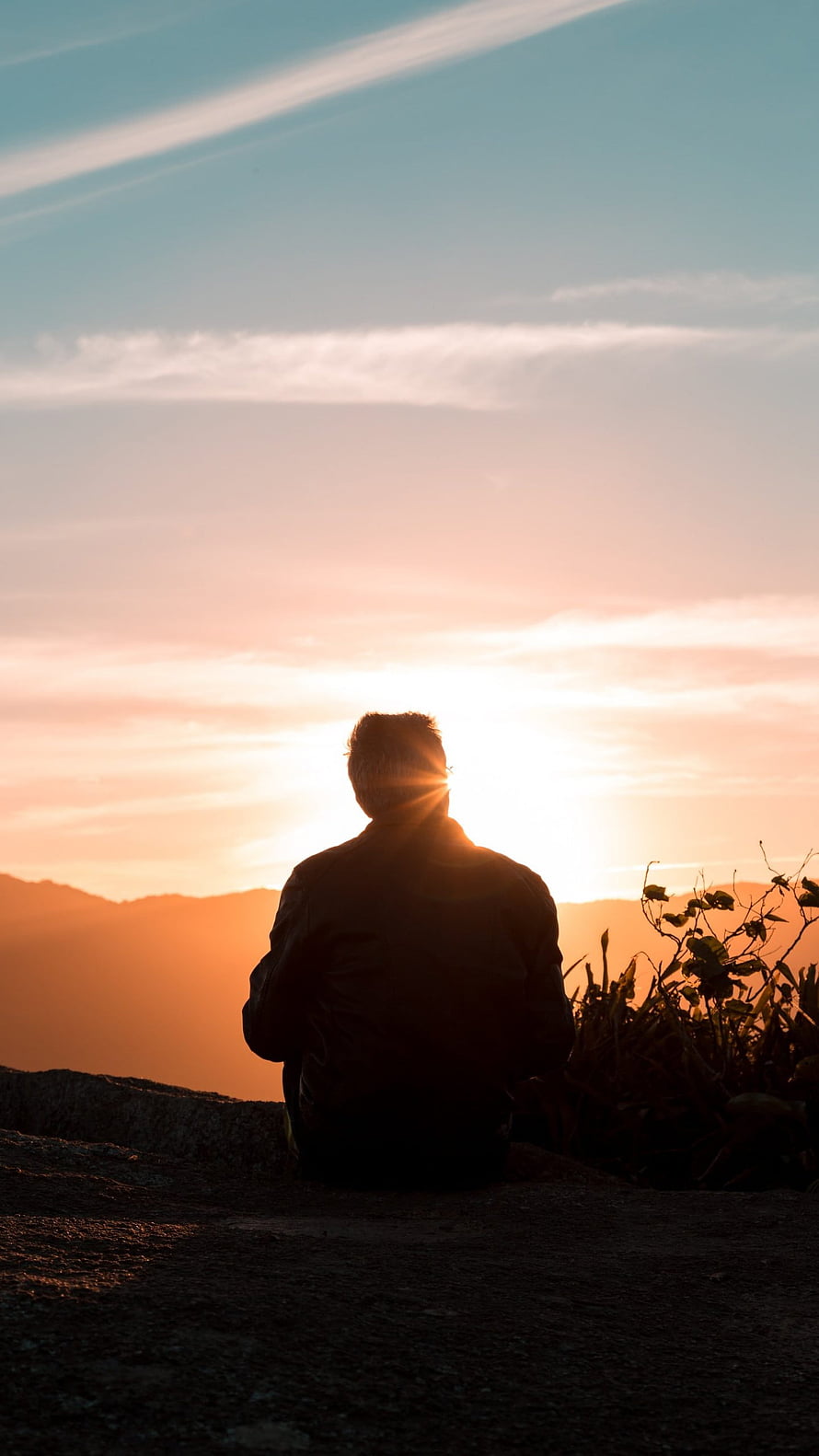 Silhouette of a Man Sitting on a Rocky Hilltop Watching the Golden Sunset Over Distant Mountains HD phone wallpaper