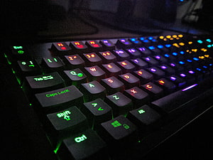 Close-up of a backlit gaming keyboard with vibrant RGB lighting in a dark setting HD wallpaper