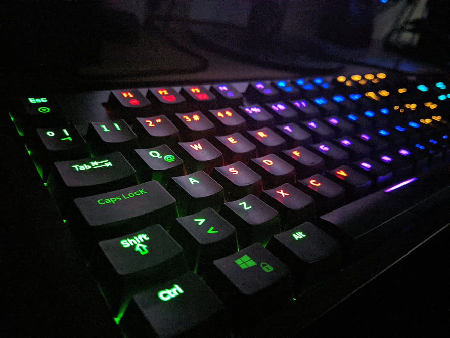 Close-up of a backlit gaming keyboard with vibrant RGB lighting in a dark setting HD wallpaper