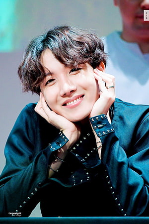 J-Hope from BTS smiling with hands on cheeks in a studded dark jacket HD phone wallpaper