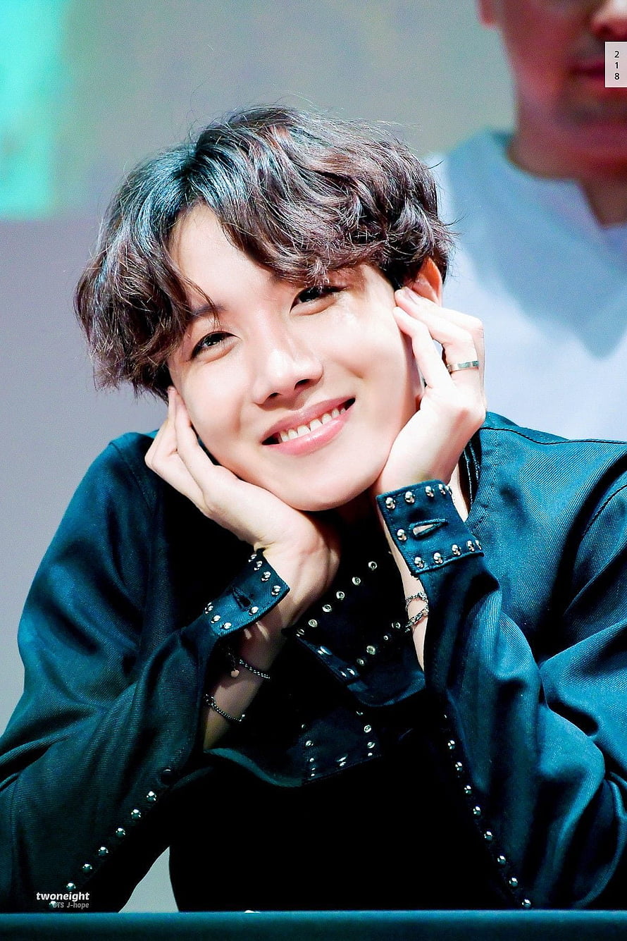 J-Hope from BTS smiling with hands on cheeks in a studded dark jacket HD phone wallpaper