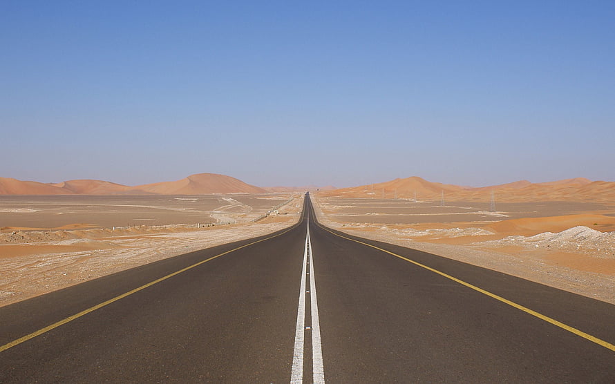 Endless Desert Highway Stretching Toward Distant Sand Dunes Under a Clear Blue Sky HD wallpaper