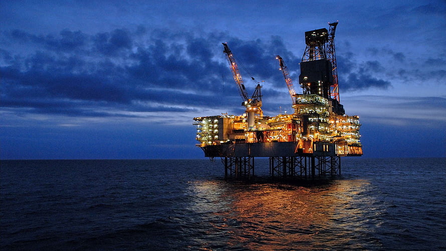 Illuminated Offshore Oil Rig Standing Alone in the Ocean at Dusk HD wallpaper
