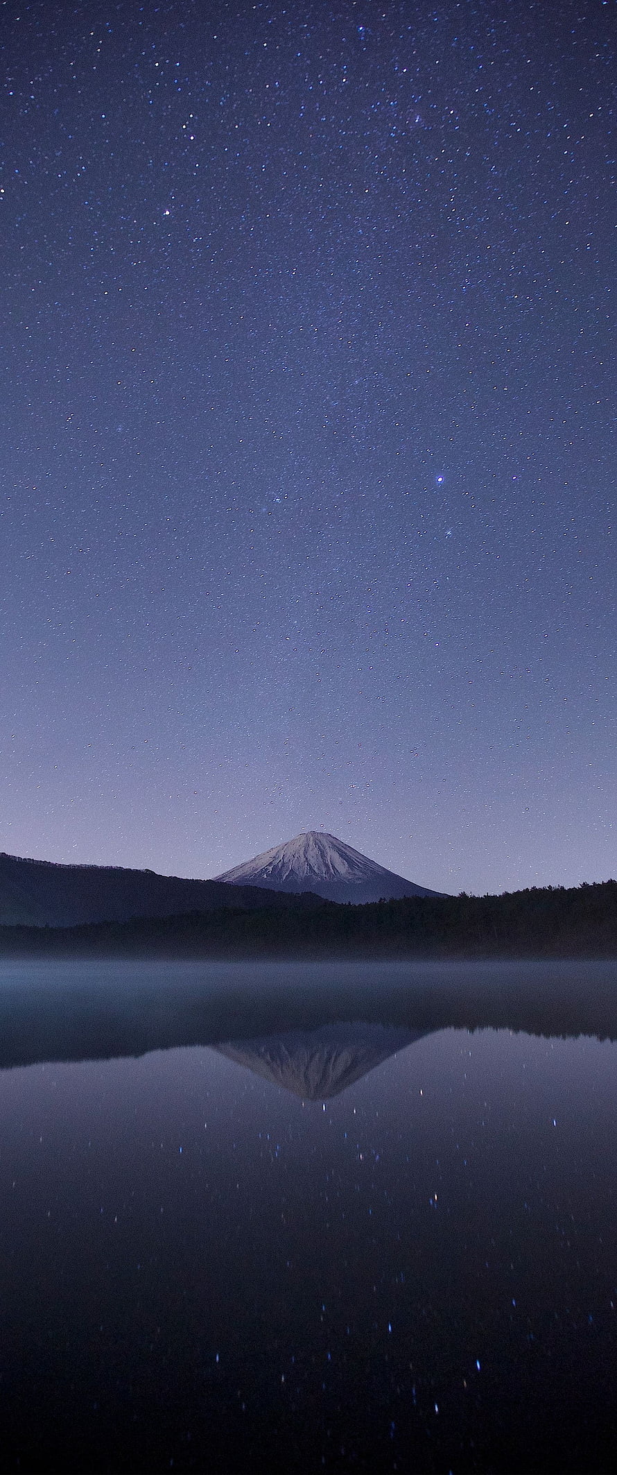 Snow-Capped Volcanic Peak Reflected in a Still Lake Beneath a Star-Filled Night Sky HD phone wallpaper