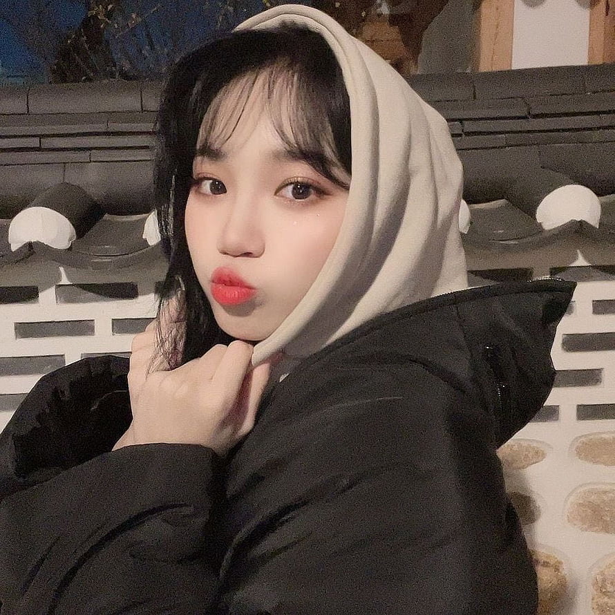 Kim Chaewon in a black puffer jacket with a beige hood against a traditional tiled wall HD phone wallpaper