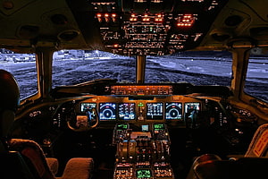 Modern Airplane Cockpit Interior at Night with Illuminated Flight Instruments and Snowy Runway View HD wallpaper