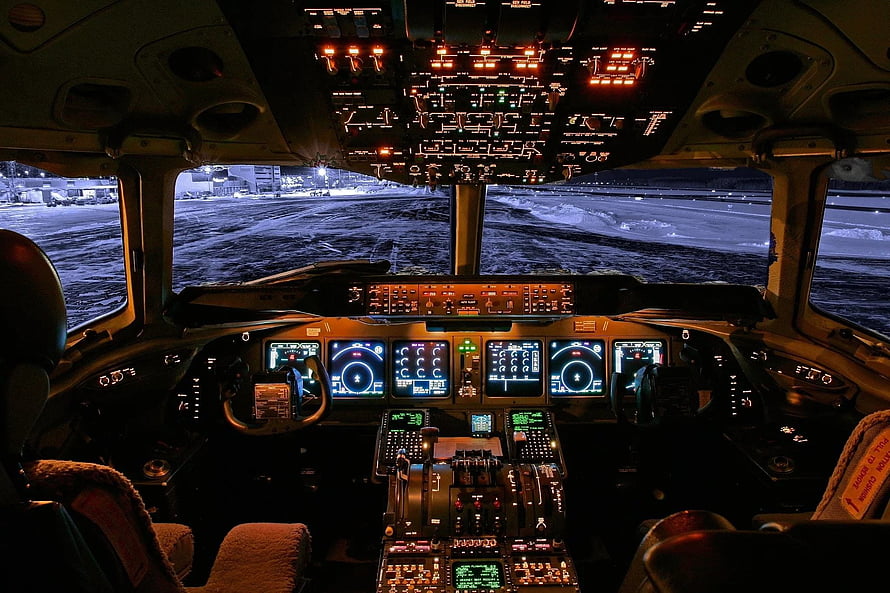 Modern Airplane Cockpit Interior at Night with Illuminated Flight Instruments and Snowy Runway View HD wallpaper