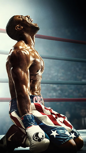Adonis Creed kneeling in the boxing ring with patriotic shorts and gloves HD phone wallpaper