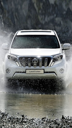 White Toyota Land Cruiser Prado splashing through water in rugged outdoor setting HD phone wallpaper