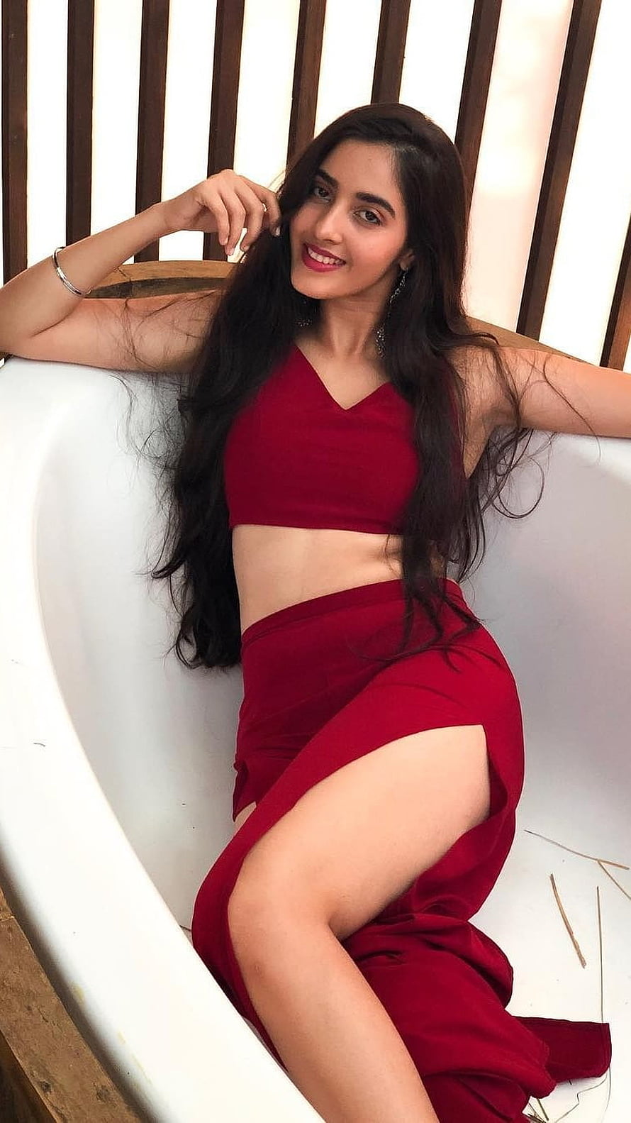 Simrat Kaur in a Red Two-Piece Outfit Reclining on a White Curved Bench HD phone wallpaper