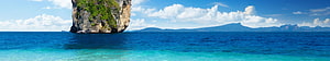 Tropical Island Limestone Cliff Rising from Turquoise Ocean Water Under Blue Sky HD wallpaper