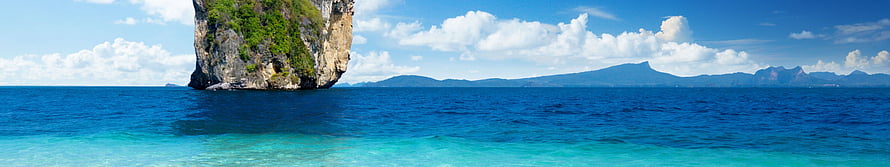 Tropical Island Limestone Cliff Rising from Turquoise Ocean Water Under Blue Sky HD wallpaper