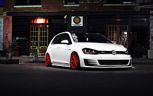 White Volkswagen Golf GTI with red wheels parked on a city street at night HD wallpaper