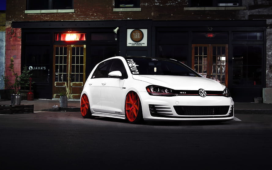 White Volkswagen Golf GTI with red wheels parked on a city street at night HD wallpaper