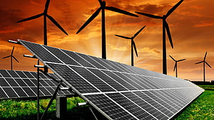 Solar panels and wind turbines in a green field under a dramatic orange sunset sky HD wallpaper