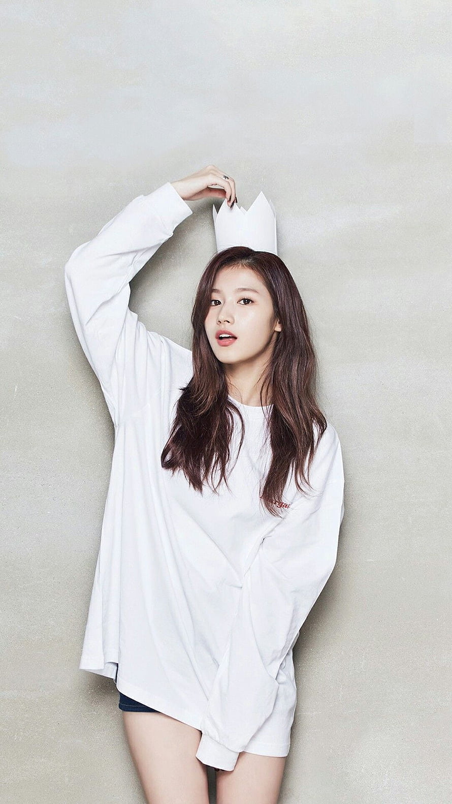 Sana Minatozaki in oversized white shirt with paper crown against neutral studio backdrop HD phone wallpaper