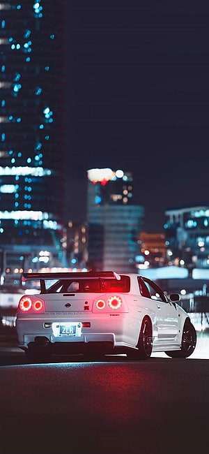 White Nissan Skyline R34 GT-R Rear View on a Night City Street with Glowing Taillights HD phone wallpaper