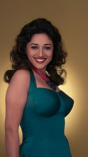 Madhuri Dixit in a teal gown with a pink scarf and beaded brooch against a warm golden backdrop HD phone wallpaper