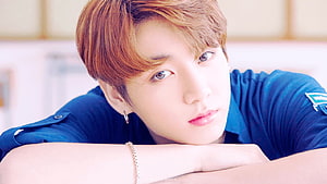 Jungkook from BTS in a blue shirt with a soft, contemplative expression HD wallpaper