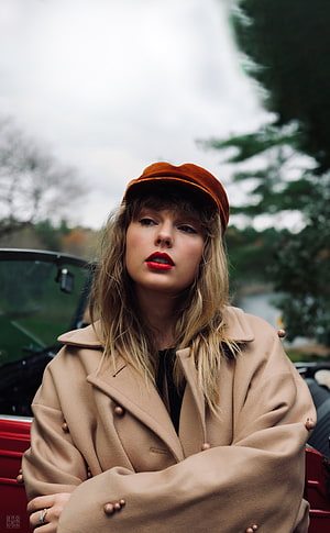 Taylor Swift in Camel Coat and Rust Cap Leaning on Red Car HD phone wallpaper