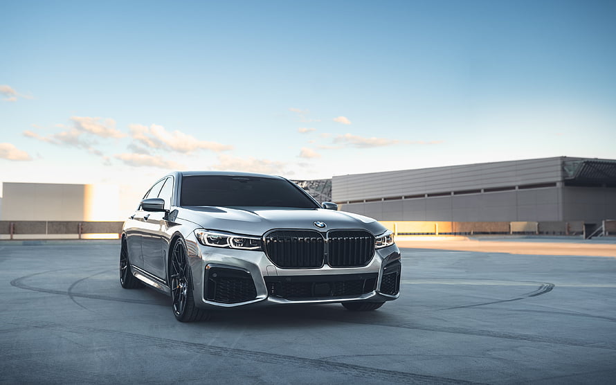 Silver BMW 7 Series Luxury Sedan Parked on Concrete Rooftop at Sunset HD wallpaper