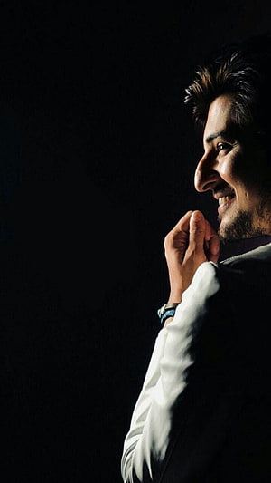 Darshan Raval in a dramatic side profile portrait with a warm smile against a dark background HD phone wallpaper