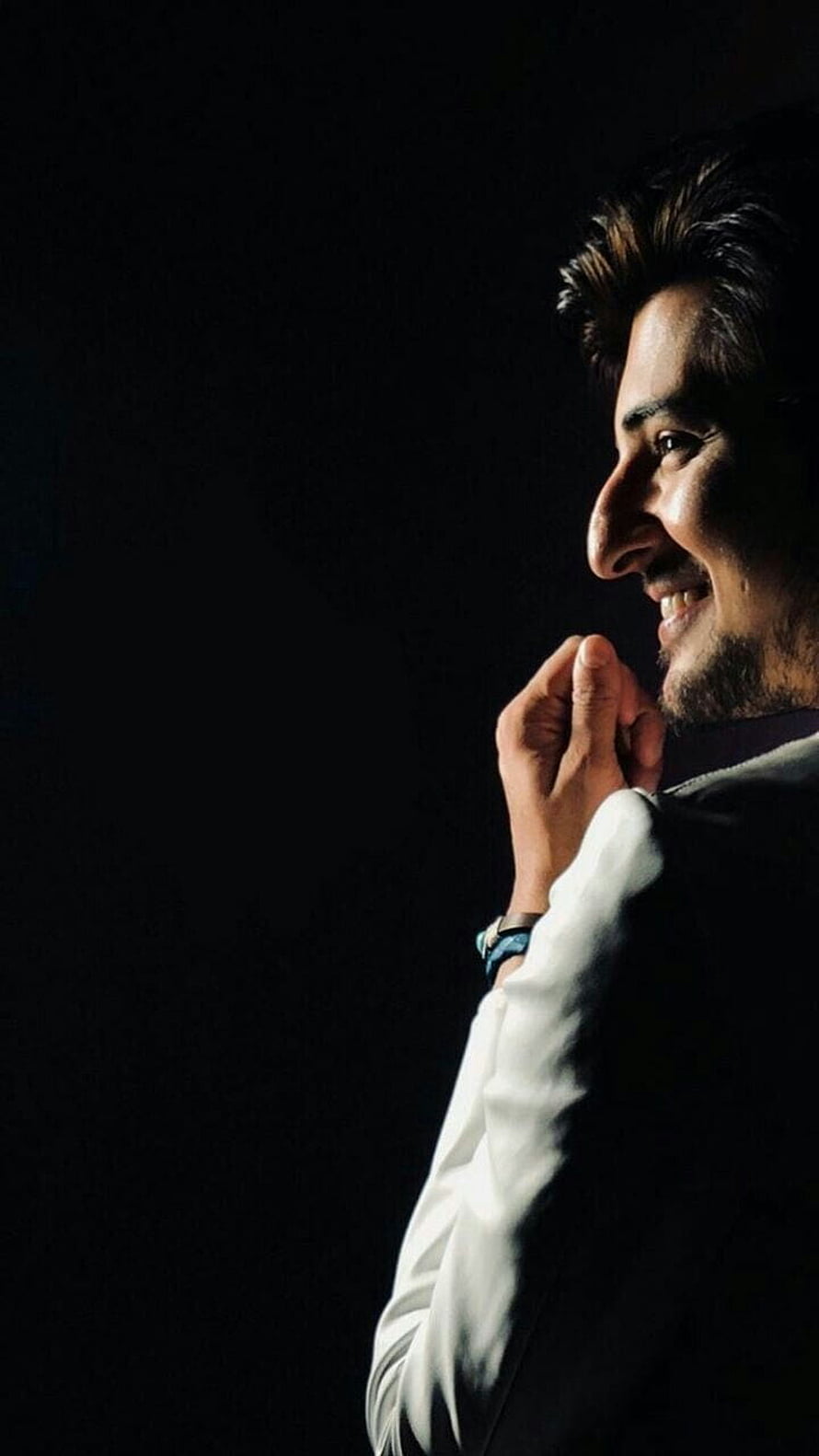 Darshan Raval in a dramatic side profile portrait with a warm smile against a dark background HD phone wallpaper