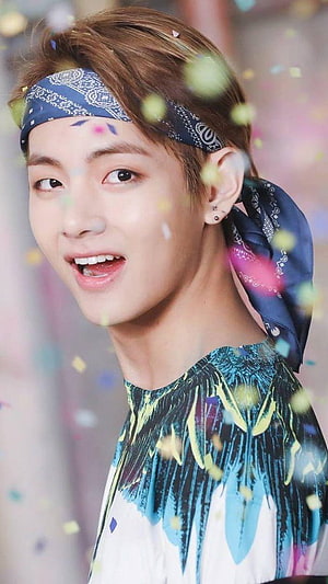 V from BTS smiling with a blue bandana and colorful confetti in the air HD phone wallpaper