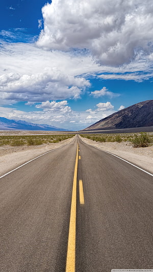 Endless Desert Highway Stretching Toward Distant Mountains Under a Bright Blue Sky HD phone wallpaper