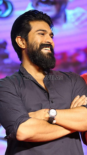 Ram Charan smiling with arms crossed at a promotional event HD phone wallpaper