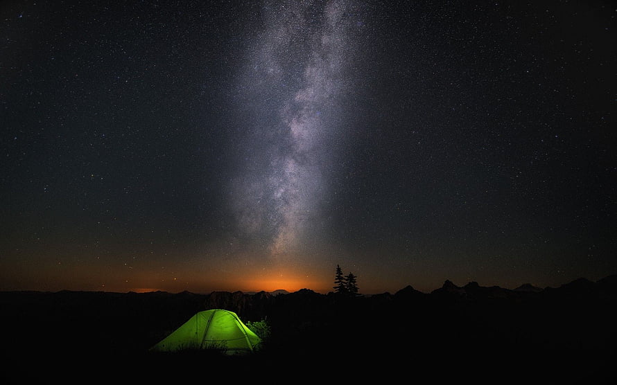 Glowing Green Tent Under the Milky Way Galaxy in a Dark Mountain Landscape HD wallpaper