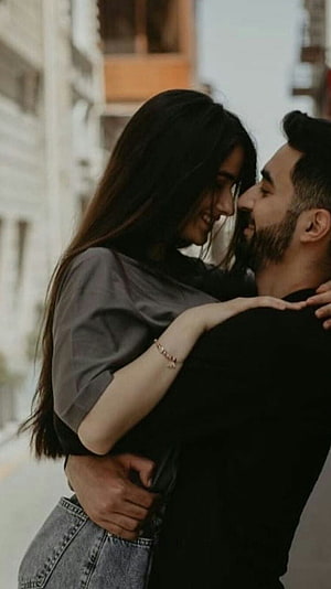Romantic couple embracing on a city street with soft natural lighting HD phone wallpaper