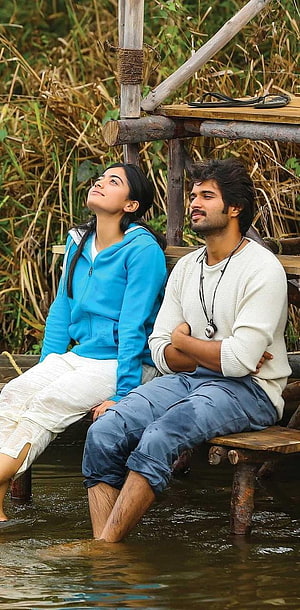 Vijay Devarakonda and Rashmika Mandanna sitting on a rustic wooden dock by the water HD phone wallpaper