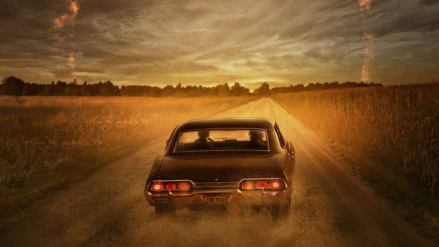 Supernatural Classic Car Driving on Dusty Country Road at Golden Hour HD wallpaper