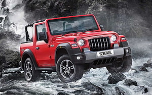 Red Mahindra Thar Off-Road SUV Driving Through Rocky Mountain Stream HD wallpaper
