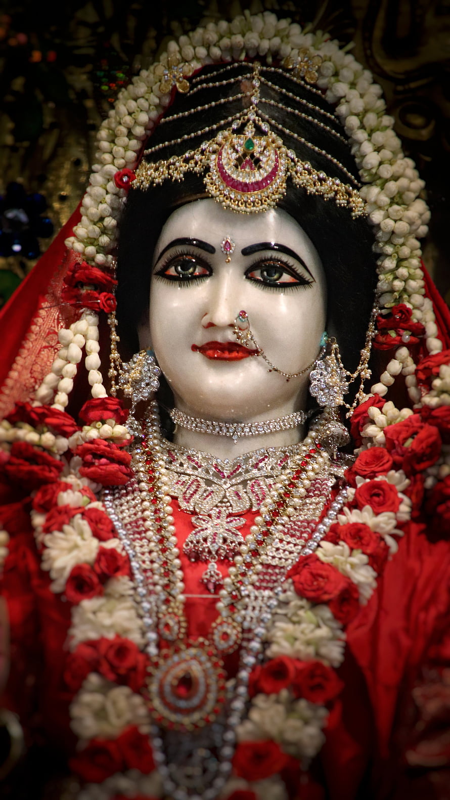 Ornate Radha Rani Murti Adorned in Red Saree, Floral Garland, and Traditional Temple Jewelry HD phone wallpaper