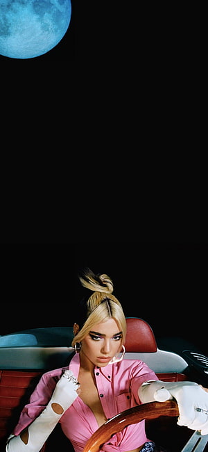 Dua Lipa in pink shirt and white gloves driving a car under a blue moon HD phone wallpaper