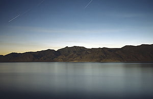 Serene Mountain Lake at Dusk with Star Trails in the Night Sky HD wallpaper