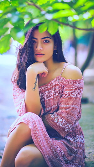 Rashmika Mandanna in a floral dress posing under green foliage HD phone wallpaper