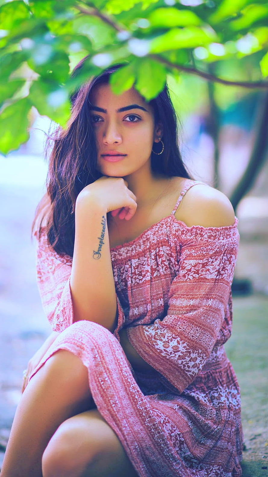 Rashmika Mandanna in a floral dress posing under green foliage HD phone wallpaper