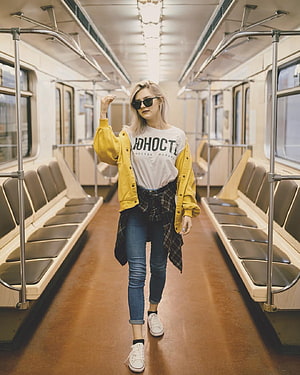Eva Elfie in a yellow jacket and sunglasses walking through a vintage subway car HD phone wallpaper
