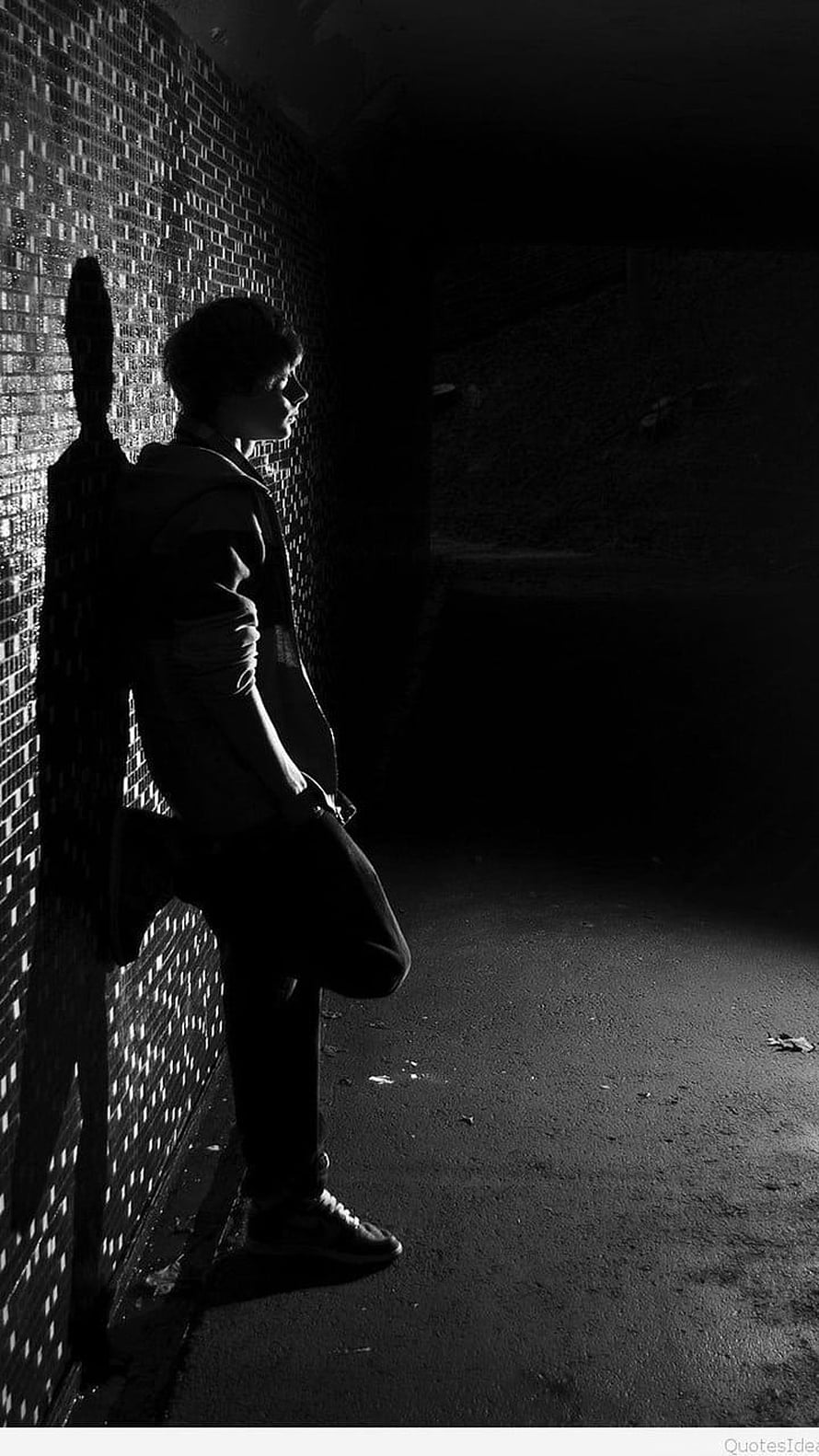 Moody Black and White Portrait of a Young Man Leaning Against a Brick Wall in a Dark Alley HD phone wallpaper