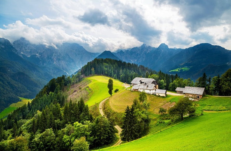 Alpine Pastoral Landscape With Farmhouses, Rolling Green Hills, and Dramatic Mountain Peaks HD wallpaper