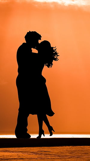 Romantic Couple Silhouette Embracing Against Vibrant Orange Sunset Sky HD phone wallpaper